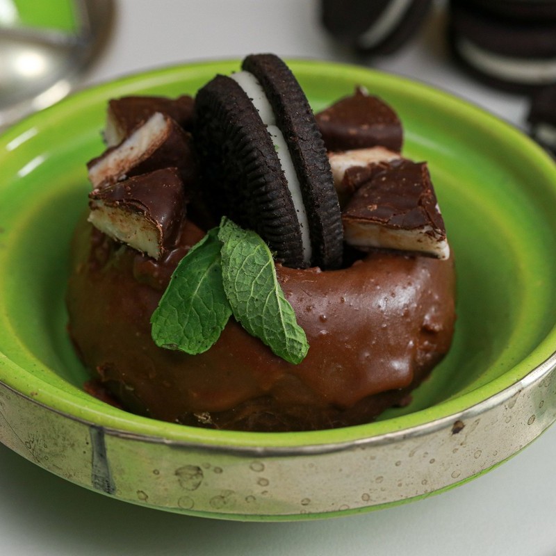 Chocolate Donut topped with Mint KinniTOOs and mint leaves in green dish with silver band