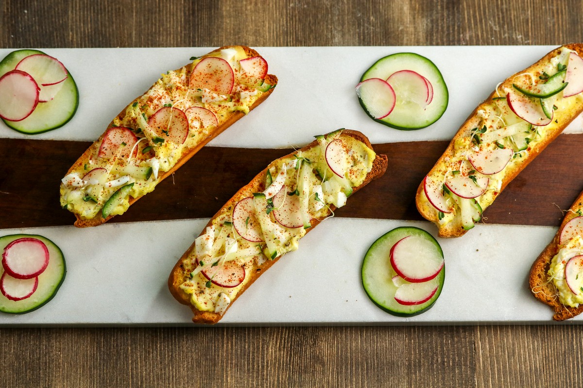 Devilled Egg Crostini on Hot Dog Buns on white & wood serving board