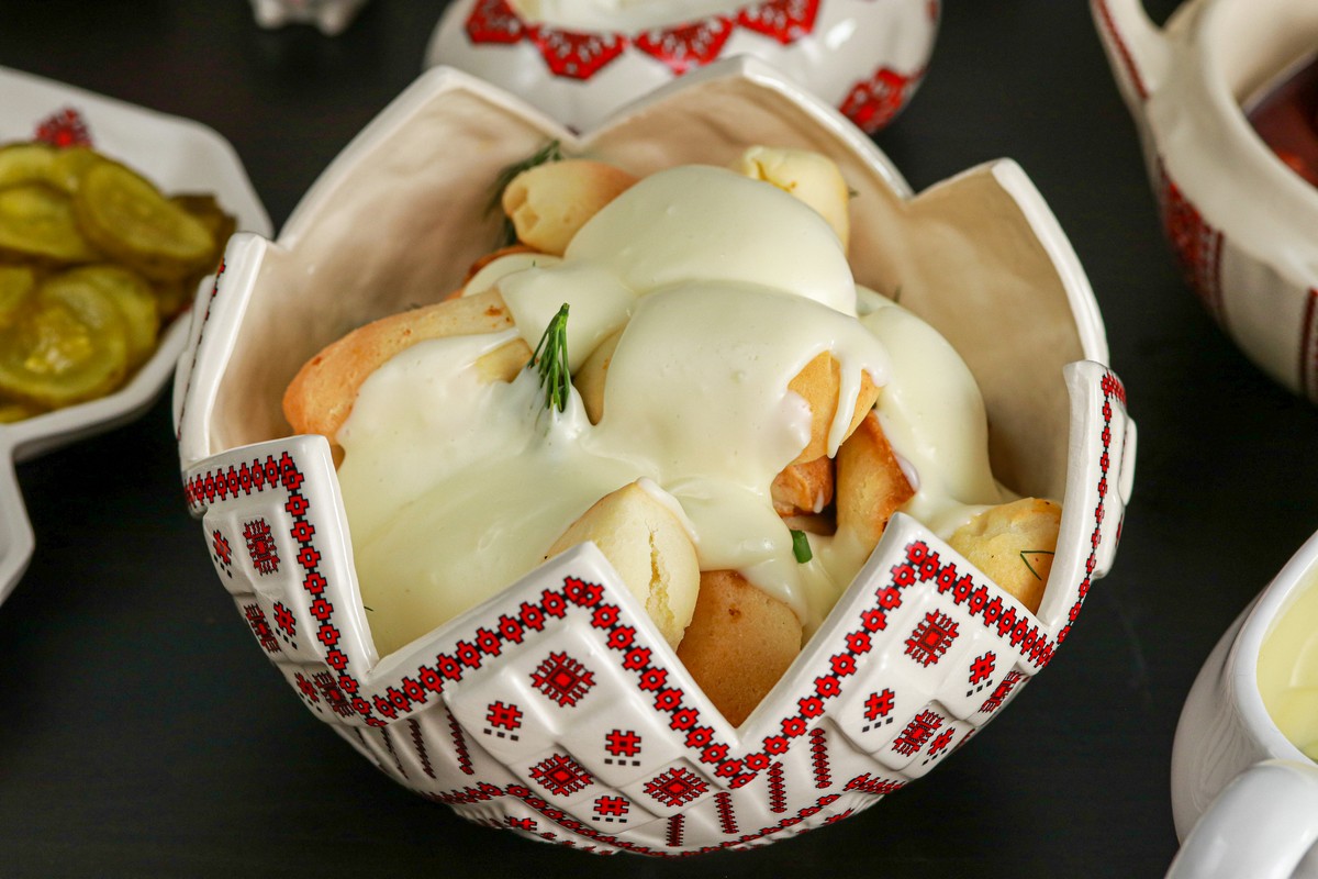 Gluten-free Pyroshky dough buns in a Ukrainian red and white dish surrounded by similar serving dishes