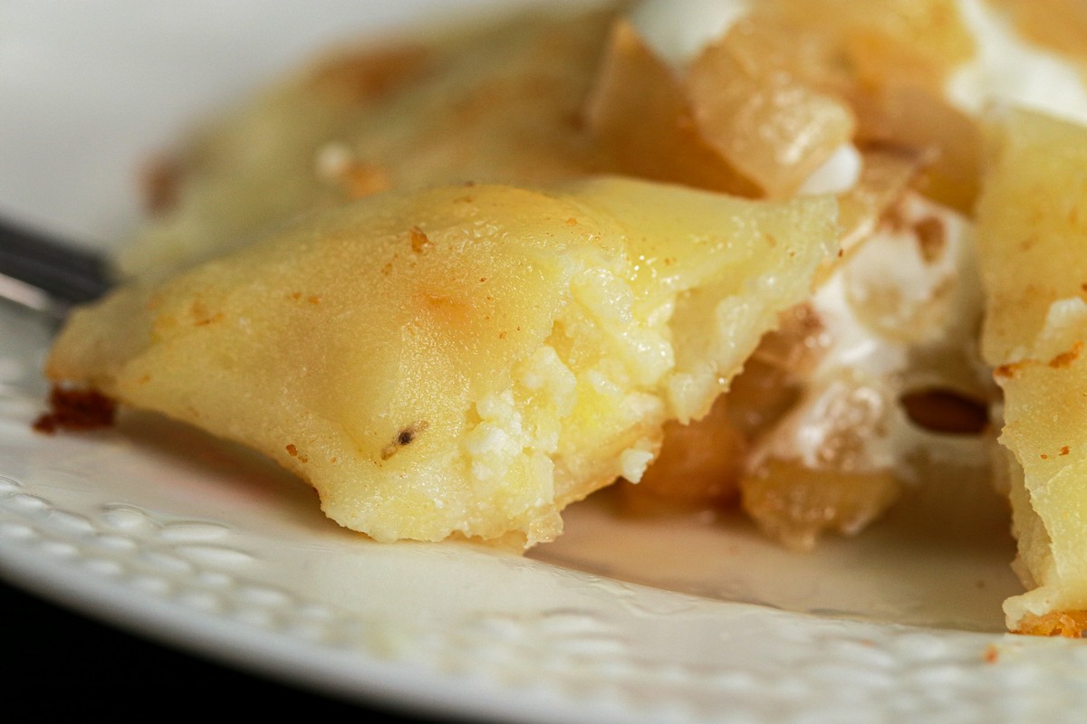 Gluten-free cottage cheese potato onion pierogi on traditional Ukrainian serving dish surrounded by others on board. 