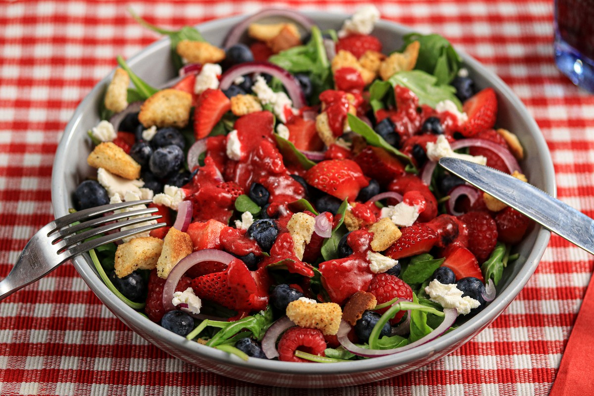 Gluten-free Arugula Berry Salad in bowl on red & white chequered table cloth