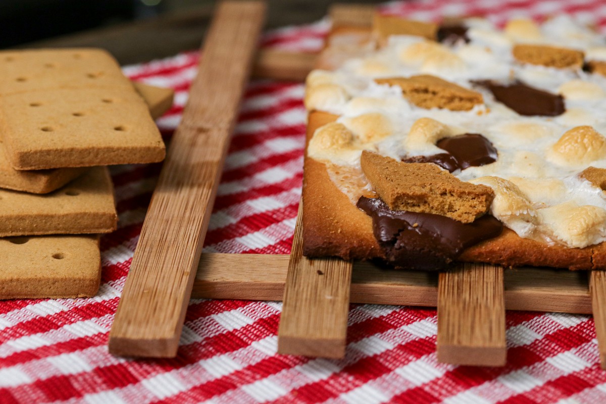 Smoreables Pizza corner on wooden cooling slat three smoreables cookies on side on red white chequered cloth